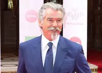 Pierce Brosnan, total schimbat în rolul Regelui Ludovic al XIV-lea. Actorul de 68 de ani are părul șaten și lung până la umeri