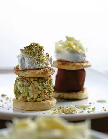 CLATITE MICI CU TRUFE DE CIOCOLATA 
INGREDIENTE  225 g faina cu praf de copt &bull; 2 lingurite praf de copt &bull; 50 g zahar pudra 
&bull; 2 oua de marime medie &bull; 350 ml de lapte smântânit &bull; 500 g mere  &bull; 1 lingurita extract de vanilie &bull; 50 g unt &bull; trufe de ciocolata negre &bull; trufe de ciocolata alba imbracate in fistic 
&bull; ciocolata alba rasa, pentru decor
MOD DE PREPARARE Se prepara clatite mici intr-o tigaie unsa cu unt; intre doua clatite se pune o trufa si se decoreaza cu ciocolata alba.
 