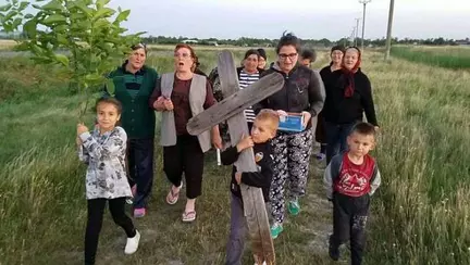 Copil obligat sa care o cruce de lemn pe un drum din Buzau