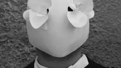 Masca "made in Romania" se poartă la Prada. Cine este în spatele acestei ținute extravagante?