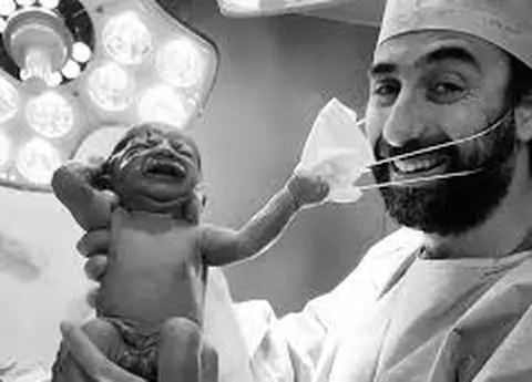 Povestea fotografiei virale cu nou-născutul care încearcă să scoată masca medicului: "Tatăl stătea lângă soţia sa, care născuse gemeni, un băiat şi o fată..."