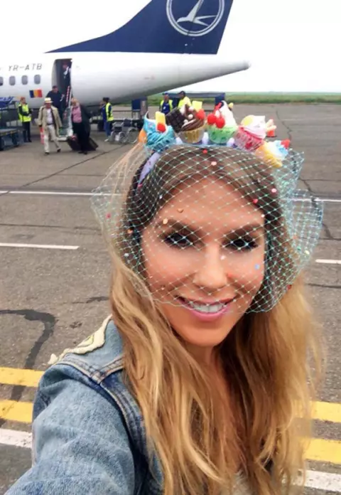 Corina face furori cu un nou accesoriu cool! Poartă la concerte o cordeluţă cu prăjituri pe cap!