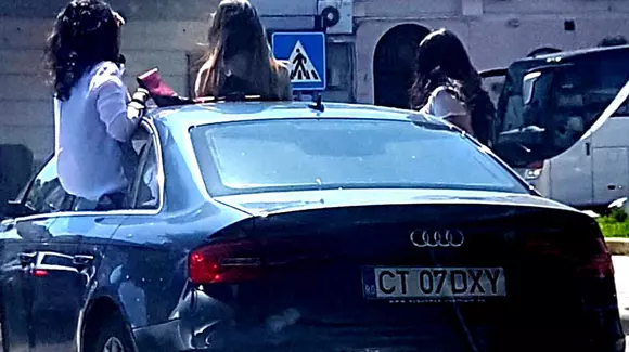 Fete filmate în trafic pe jumătate ieșite din mașină, amendate de polițiști (Video)