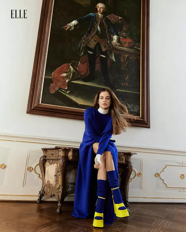 Cleo poartă capă, maletă și șosete, toate Ami Amalia, și pantofi, Versace.