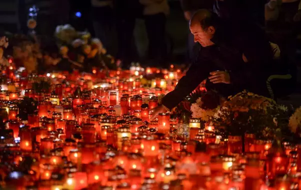 Persoane aprind lumanari la monumentul dedicat memoriei celor 64 de tineri ce si-au pierdut viata in incendiul din Club Colectiv, in Bucuresti, duminica, 30 octombrie 2016.