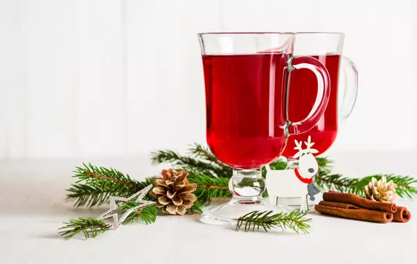 A glass of red hot mulled wine on a light background. Christmas and New Year greeting card. Copy space.