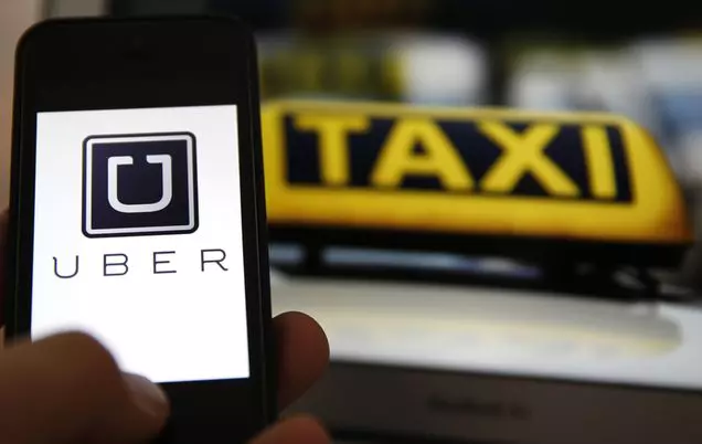 File illustration picture showing the logo of car-sharing service app Uber on a smartphone next to the picture of an official German taxi sign