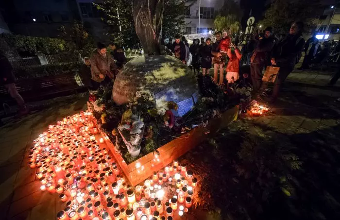 Persoane aprind lumanari la monumentul dedicat memoriei celor 64 de tineri ce si-au pierdut viata in incendiul din Club Colectiv, in Bucuresti, duminica, 30 octombrie 2016.