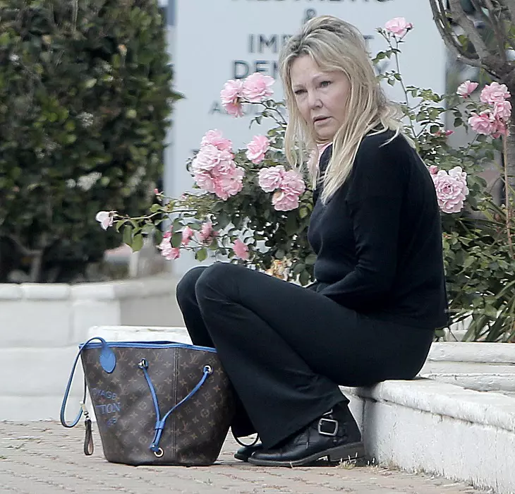 Heather Locklear looks lost in thought and somewhat disheveled whilst sitting on a curb waiting for a ride home in the scorching LA heat.