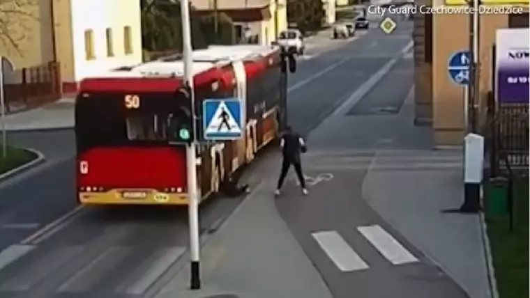 O tânără a fost la un pas de a fi strivită de un autobuz după ce prietena ei a împins-o pe stradă în glumă - Tanara cade langa rotile autobuzului rosu