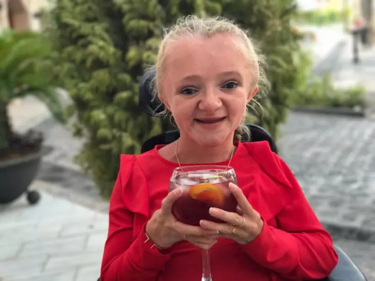 O tânără care are o boală genetică rară poate suferi fracturi osoase și de la un sughiț - Marie imbracata in rosu, cu un pahar in mana