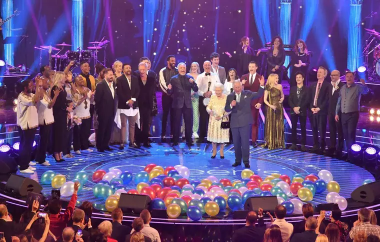 Regina Elisabeta a II-a și Prințul Charles, pe scena Albert Hall, cu ocazia concertului aniversar. (Momentul în care Charles îi spune Reginei 