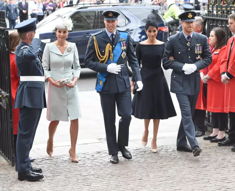 Meghan îl ține strâns de braț pe Harry, în timp ce Kate merge puțin mai în spatele lui William.