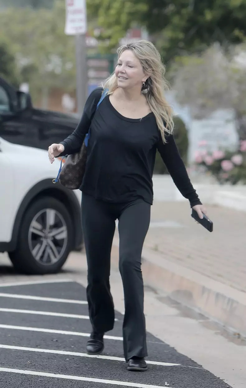Heather Locklear looks lost in thought and somewhat disheveled whilst sitting on a curb waiting for a ride home in the scorching LA heat.