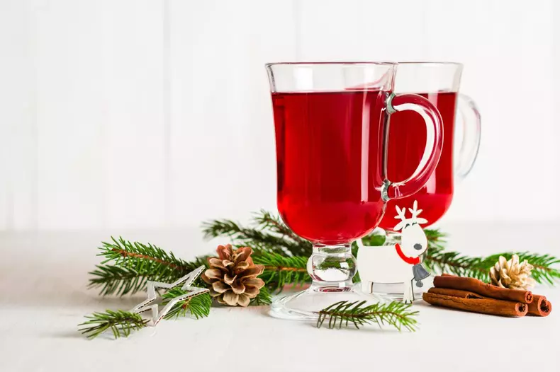 A glass of red hot mulled wine on a light background. Christmas and New Year greeting card. Copy space.