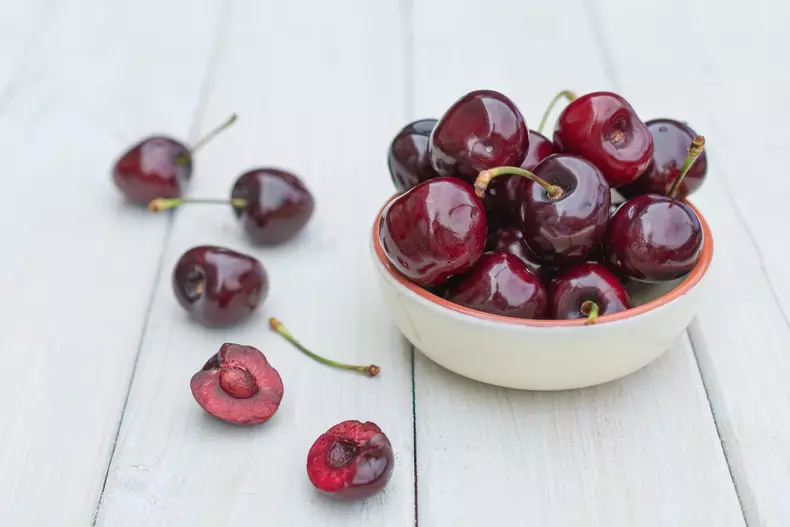 Bowl filled with cherries on a wooden table