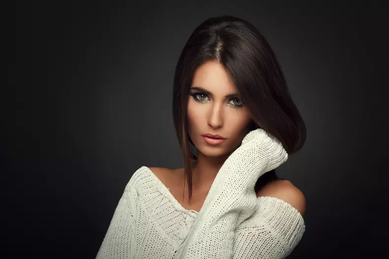 Beautiful,Woman,In,White,Sweater,Posing,In,Studio,On,Dark