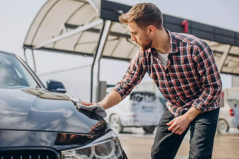 Young man wiping his car after car wash