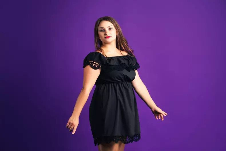 Plus size fashion model in black dress, fat woman on purple background