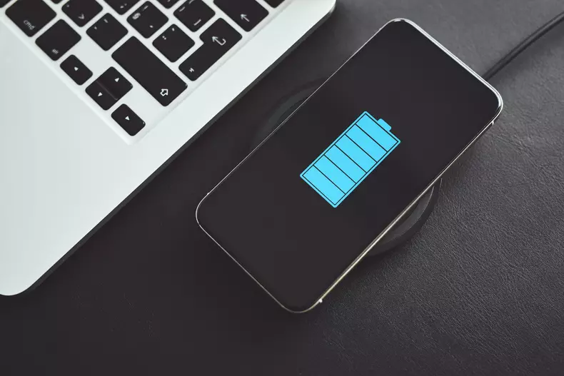 Top view of mobile phone while charging wirelessly next to laptop