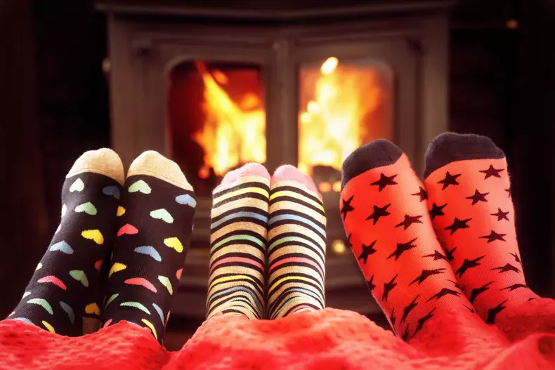Feet in wool socks near fireplace in winter