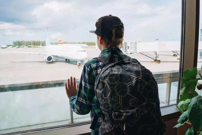 Caucasian,Boy,In,Airport,Watching,With,Backpack,Waiting,For,Plane.