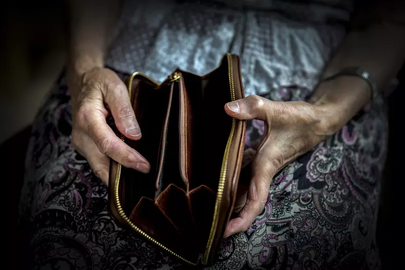 An,Elderly,Man,Holding,An,Old,Coin,Purse,And,Coins