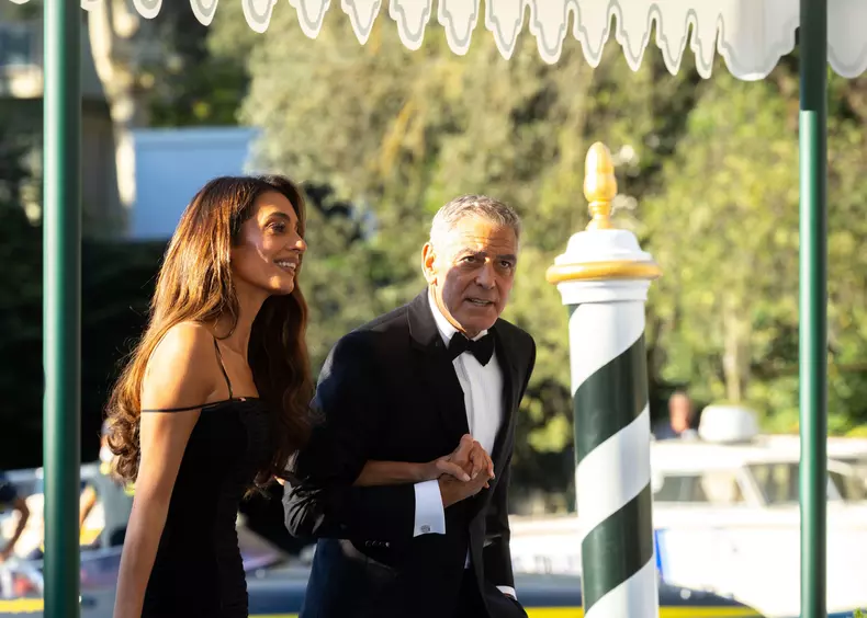 Venice, Italy - September 02, 2026: George Clooney and Amal Clooney dressed in formal wear at the Venice Film Festival, with a scenic background of gr