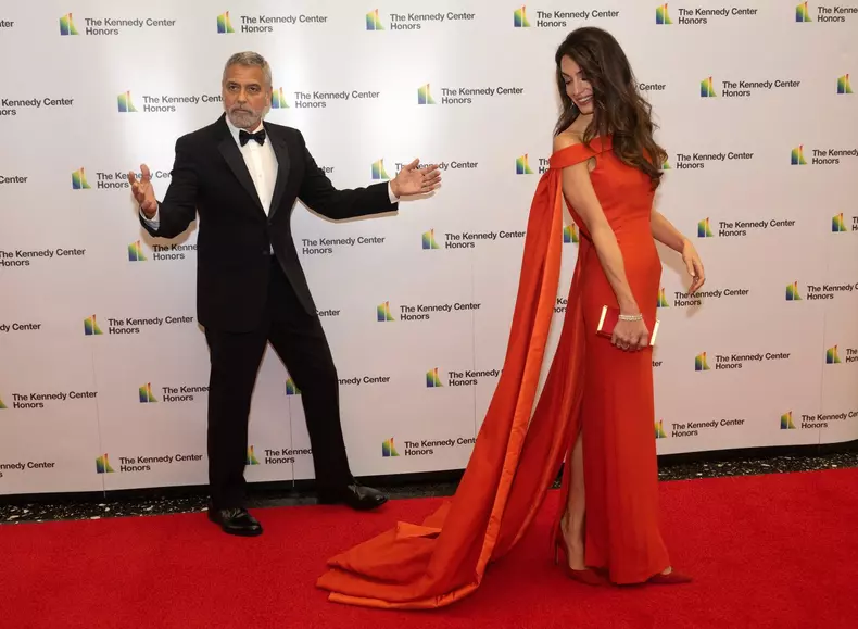 Washington DC, USA. 03rd Dec, 2022. George Clooney kids the photographers after adjusting the train on his wife, Amal's dress as they prepare to pose for photos as they arrive for the formal Artist's Dinner honoring the recipients of the 45th Annual Kenne