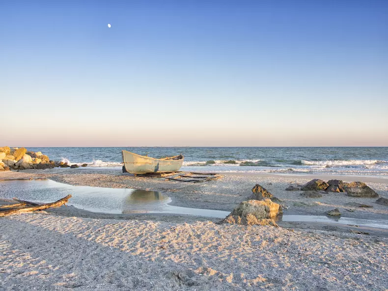 Moon,Rising,And,A,Boat,On,A,Solitary,Wild,Beach