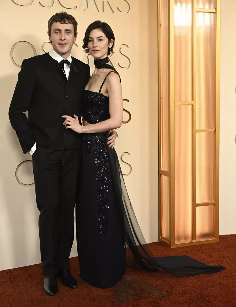 Paul Mescal într-un costum negru boxy și Gracie Abrams într-o rochie elegantă de seară la sosirea pe covorul roșu al Premiilor Oscar 2026.