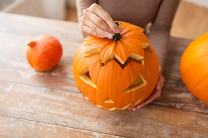 close up of woman with halloween pumpkin at home