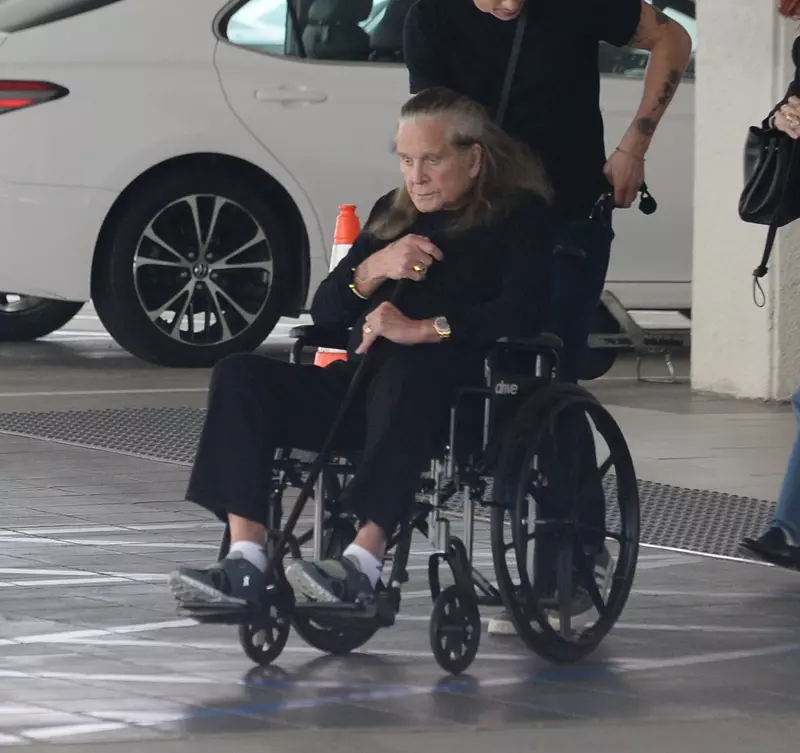 Ozzy Osbourne este dus printr-o parcare intr-un scaun cu rotile
