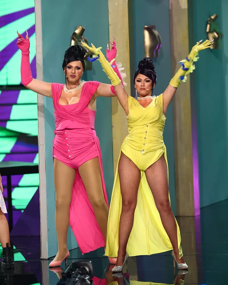 Două vedete transformate spectaculos pe scena emisiunii "Te cunosc de undeva!" 2025! Marian Capet și Doinița Oancea intră în pielea celebrelor Cardi B și Megan Thee Stallion, purtând costume vibrante și atitudine de superstar. Cu ținute extravagante – roz și galben – mănuși lungi și accesorii îndrăznețe, cei doi surprind prin expresivitate și energie